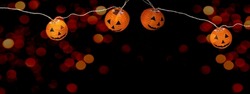 Happy HALLOWEEN party celebration background banner Panorama - Fairy lights, String of lights with funny orange glowing Halloween pumpkins and bokeh lights in the dark night