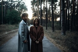 romantic couple in the forest in a coat, gloomy date sadness and peace.