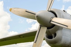 A fragment of airplane wing with four-bladed aircraft propeller against blue sky