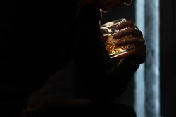 glass with whiskey brandy in a man's hand on a black background. male silhouette with a glass of whiskey on a black background