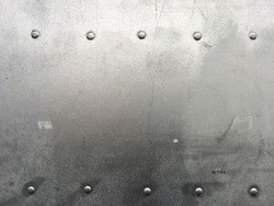 Riveted metal background, detail metal textured background from aircraft. Old grunge metal fragment of protective structure made of metal plates sheets assembled with button head rivets.
