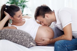 Future dad kissing belly of his pregnant wife