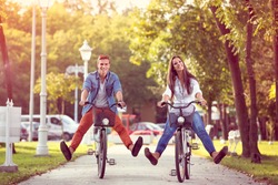 Happy autumn funny young couple riding on bicycle