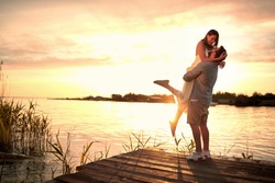 Enjoying By The River.Romantic smiling couple in love dating at sunset at river.