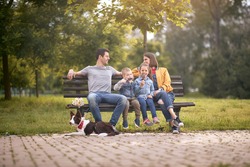 kids eating ice cream, enjoying with their parents smiling, sitting on a bench in park