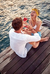 Bird-eye view of a young couple having fun while enjoying a juicy watermelon on the dock on the seaside on a beautiful day. Love, relationship, holiday, sea