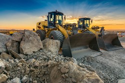 Two excavators moving stone and rock in a construction site