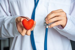 A doctor or healthcare professional holds heart shape in one hand and stethoscope in other. Concept photo for diagnosing and determining the causes of the onset of heart and cardiovascular diseases