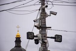 Concept photo of tracking God, religion, church for parishioners and people. Lots of street security cameras on a lighting pole in the foreground and the gilded dome of a church in the background