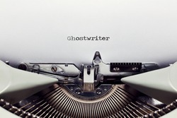 The word ghostwriter typed on the paper with a vintage typewriter. Close up flat lay view