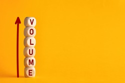 The word volume on stacked wooden cubes with arrow. Increasing music volume or production quantity or capacity in business concept. 