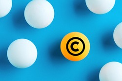 Copyright icon on yellow ball on blue background. Property and intellectual rights protection.