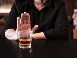 Man refuses or rejects to drink alcohol at the pub. Alcohol addiction treatment, sobriety and drinking problem.