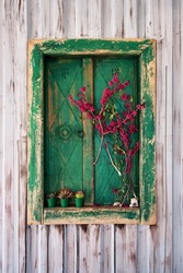 Green wooden antique window frame with shutters and decorated with flowers on steel wall plate.