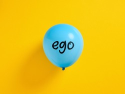 Inflated blue balloon with the word ego and a pin. Selfishness or inflated extreme ego concept.