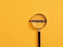 Magnifier focuses on the possible side of the word impossible. It is possible motivational inspirational concept.