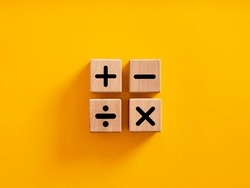 Basic mathematical operations symbols. Plus, minus, multiply and divide symbols on wooden cubes on yellow background. Mathematic or math education and basic calculations for business concept.