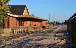 Outback town of Mildura has a disused railway station platform and track and is caught in the morning sun