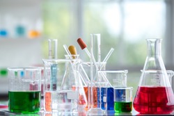 Chemical laboratory glassware with various colored liquids on table