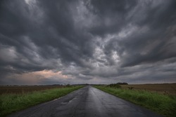 WEATHER - Dramatic black rain clouds over fields and country road