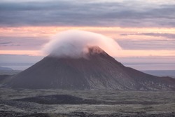 Keilir mountain in Reykjanes peninsula in Iceland shot in summer at sunset, cloud covering the top of the mountain backlit by the setting sun