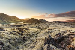 Sunset over Reykjanes peninsula, close to Reykjavik in Iceland, moss grown lava covering the landscape with mountains and a small lake in the background