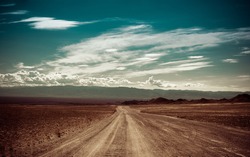 Empty rural road going through prairie under cloudy sky in Charyn canyon. State National Paleontology Park in Kazakhstan. Vintage style processing image