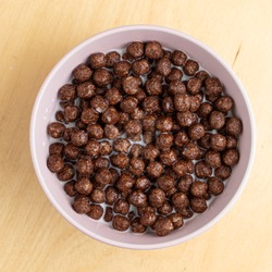 Top view of full bowl of chocolate balls with milk