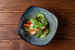 Simple vegetable salad with cucumbers and tomatoes on wooden table, top view