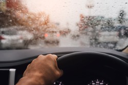  rain droplet on car windshield. driver in traffic on a cloudy day bad weather condition during storm, The concept of preventing accidents from using car using road in the rainy season.