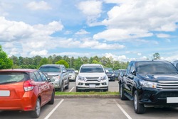 Car parked in asphalt parking lot and one empty space parking  in nature with trees, beautiful cloudy sky background .Outdoor parking lot with fresh ozone and green environment concept