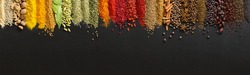 Wide variety spices and herbs on background of black table, with empty space for text or label.