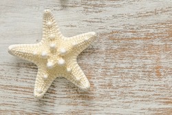  White starfish on white shabby chic board background.Summer nautical decor.Background in a marine style