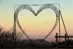 Beautiful heart shaped wire frame with pink lights at sunset 
