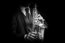 Detail of Saxophone and man hands isolated against black background. Close up studio portrait, black and white image.