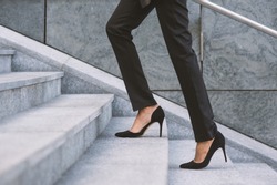 Legs and feet detail of businesswoman climbing stairs outdoors in Milan.
