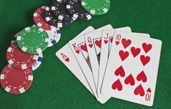 a royal flush of hearts with poker chips scattered