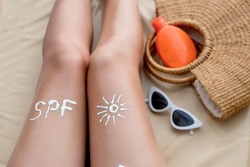 Text SPF written with sun protection cream on legs woman. Sun protection. Suncream, on her smooth tanned legs. Sunblock