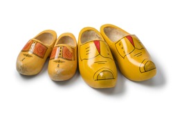 Two pairs of traditional yellow Dutch wooden shoes isolated on white background