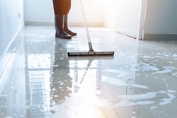 Janitor squeegee water on the floor hallway office building or walkway after school and classroom work job with sun light background. Wet floor or cleaning service house maid concept.