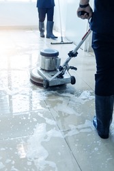 Janitor use floor scrubber machine on the floor hallway office building or walkway after school and classroom work job with sun light background. Wet floor or cleaning service house maid concept.