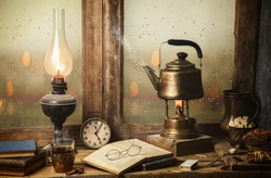 Classic still life with hot tea pot placed with illuminated vintage lamp, old books, cup of tea on rustic wooden table. 