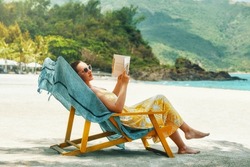 Vacation Beach Summer Holiday Concept. Woman reading book at beach resort during summer vacation.