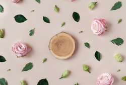 Wooden podium on trendy pastel beige background with flower buds, leaves, petals. Abstract cosmetics composition backdrop with roses. Beauty layout. Summer, aroma water concept