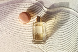 glass perfume bottle on a sandy textured background with long shadow. Summer vocation fragrance concept