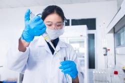 Interior of clean modern white medical or chemistry laboratory background. Laboratory scientist working at a lab with micro pipette and test tubes. Laboratory concept with Asian woman chemist.