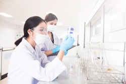 Interior of clean modern white medical or chemistry laboratory background. Laboratory scientists working at a lab with test tubes. Laboratory concept with Asian woman chemists.