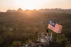 asian man with malaysian flag of malaysia on top of the mountain