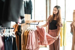 beautiful asian shopping woman looking at some clothes in the store