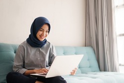 portrait of beautiful muslim woman who is very happy to see the results of her efforts on laptop at office